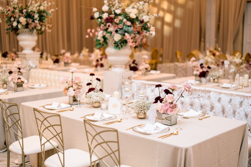 Reception tables with pink floral centrepieces and gold chairs by GPS Decors