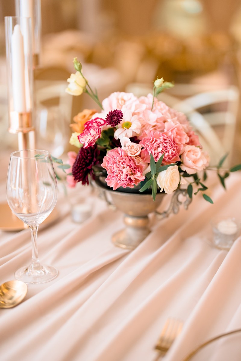 Low centrepiece of pink and burgundy roses on a blush linen table by GPS Decors