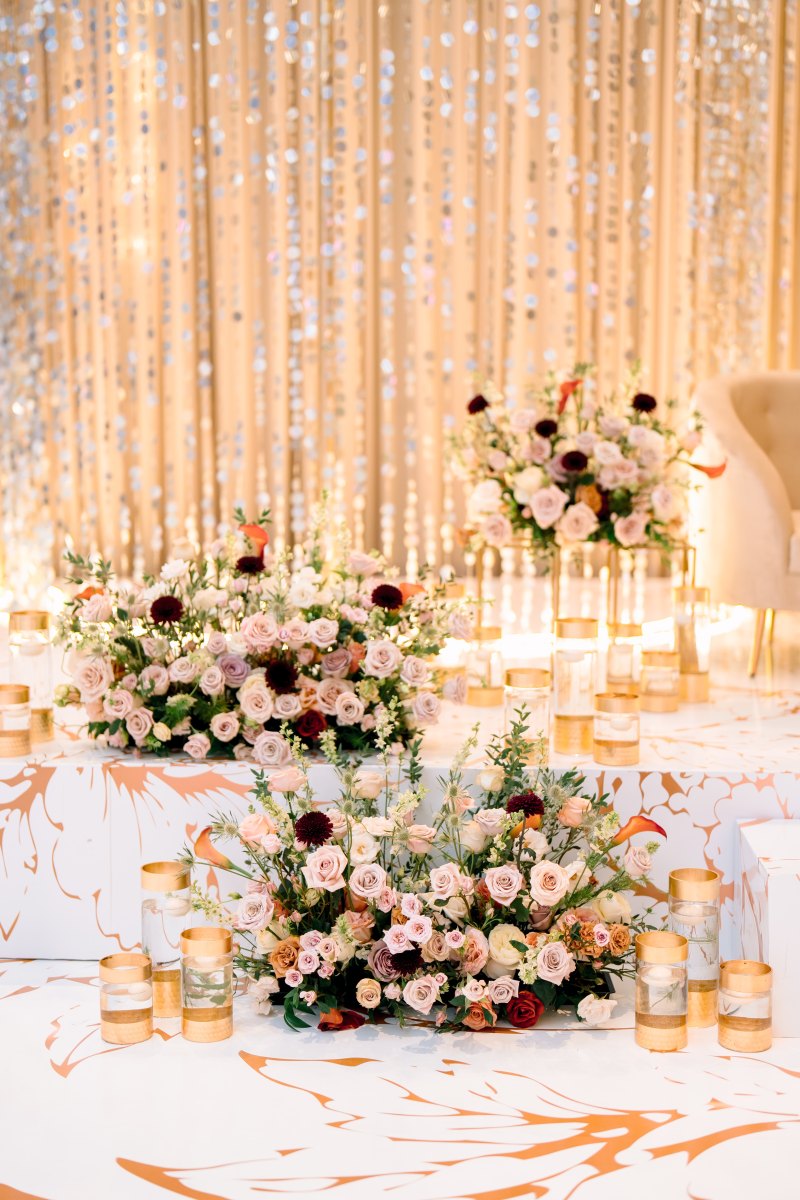 Sweetheart table with low pink and white florals before a crystal curtain by GPS Decors