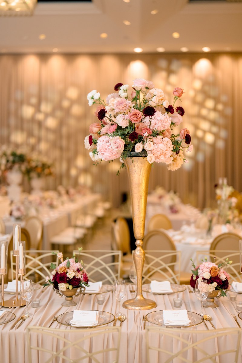Tall pink and white floral centrepiece on a gold stand above reception tables by GPS Decors