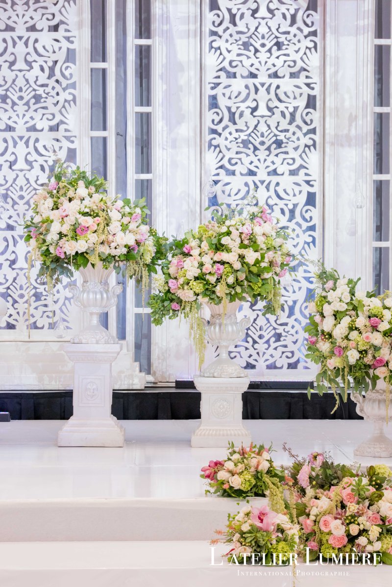 White jali backdrop with pink and white floral pedestals at a reception by GPS Decors