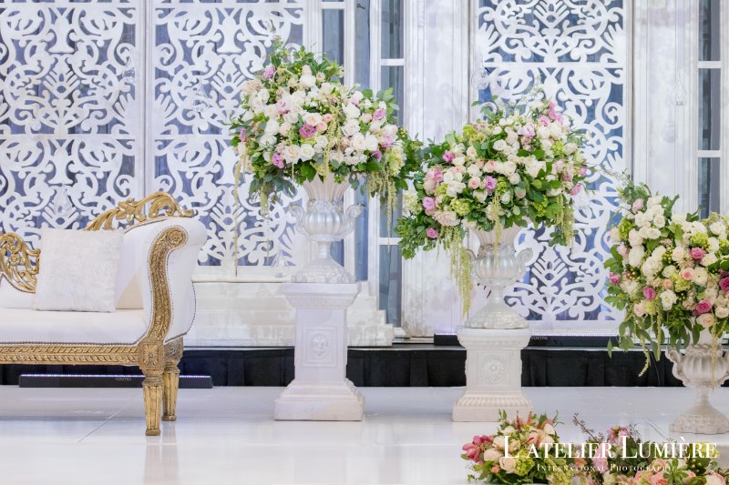 White pedestals topped with pink and white florals before a jali backdrop by GPS Decors
