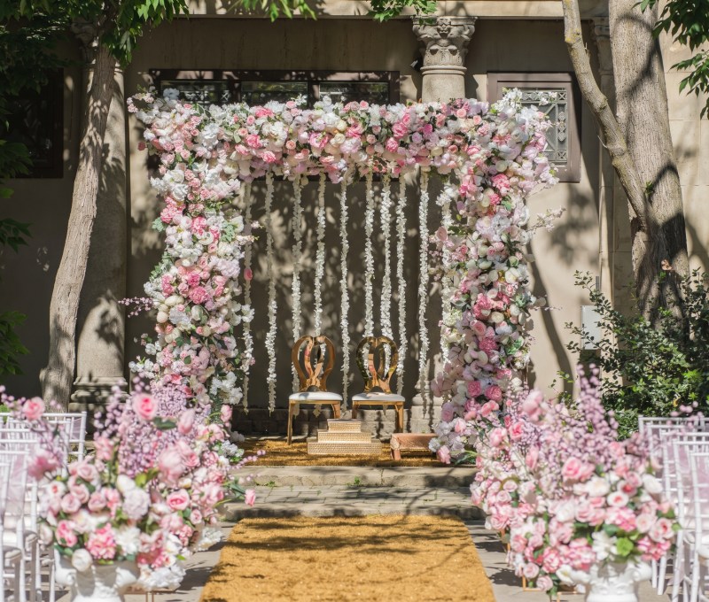 Pink and white floral mandap with hanging floral strands and a petal aisle at Liberty Grand by GPS Decors