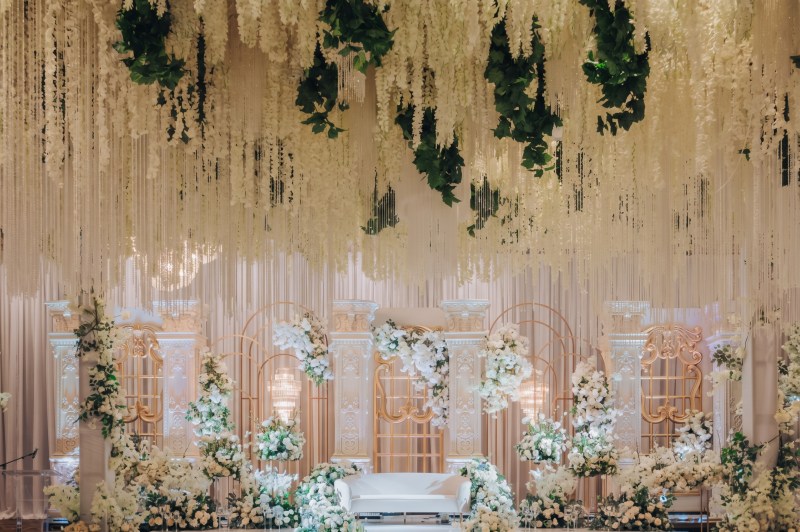 White floral arch stage beneath a hanging greenery and white wisteria ceiling at Bellvue Manor by GPS Decors