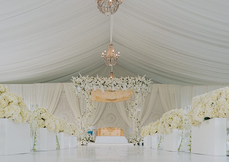 Draped white tent reception with a crystal chandelier by GPS Decors