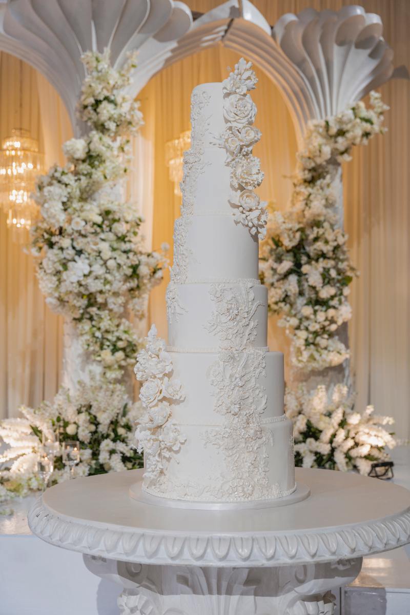 White wedding cake framed by white florals and arches by GPS Decors