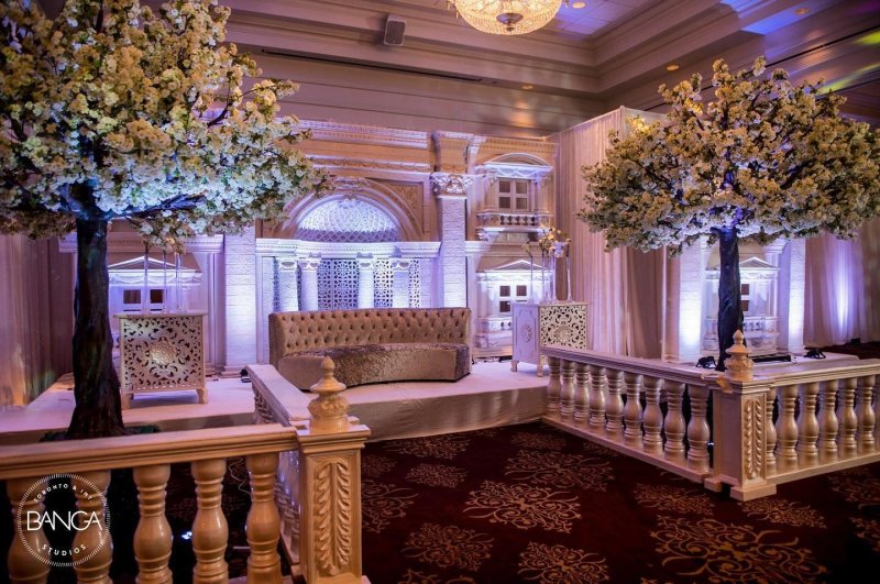 Grand ornate wedding stage with gold accents and chandeliers by GPS Decors