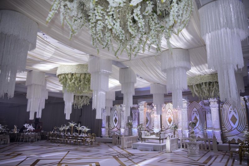 Grand wedding reception with crystal chandeliers and white floral pillars by GPS Decors