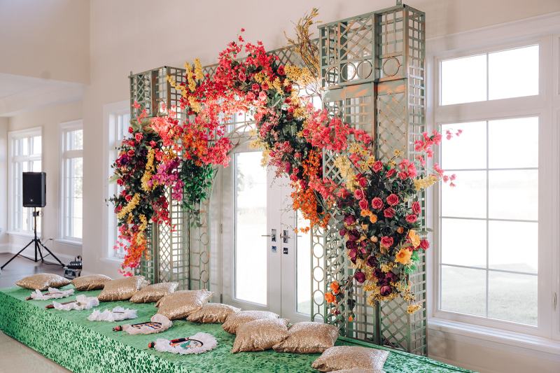 Orange and pink floral arch around French doors with floor seating by GPS Decors