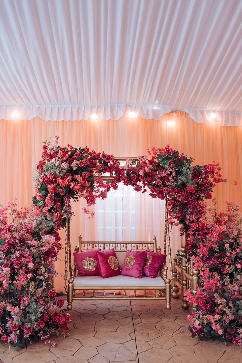 Pink and red floral arch over a swing seat for a pre-wedding event by GPS Decors