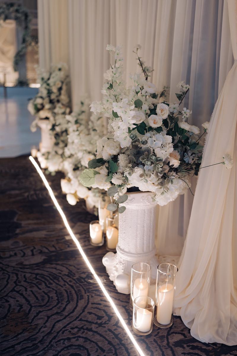Aisle lined with candles and white florals at a reception by GPS Decors