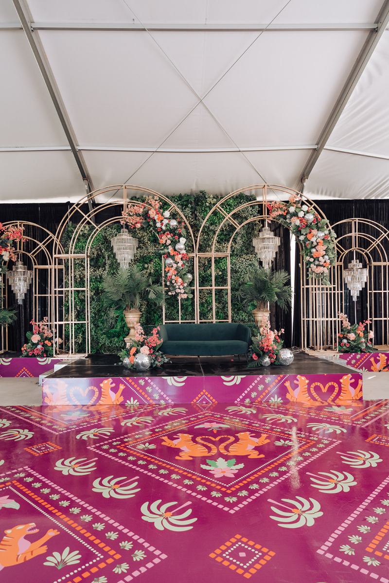 Tented sangeet stage with arched mirrors and a pink printed dance floor by GPS Decors