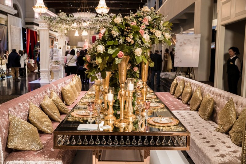 Long mirrored table with gold vase florals and pink tufted banquette seating by GPS Decors