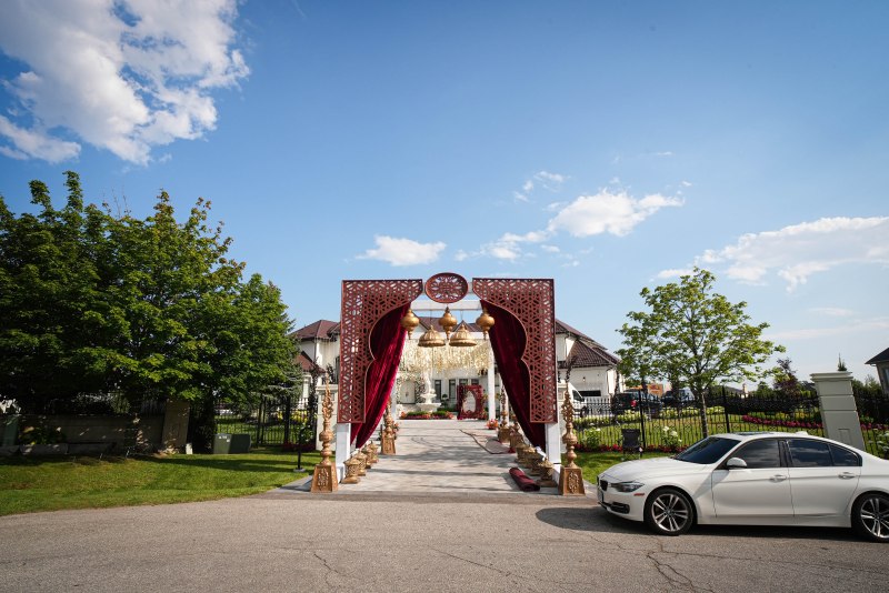 Carved red and gold entrance archway for an outdoor sangeet by GPS Decors