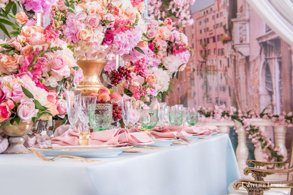 Pink rose and peony centrepiece in a gold vase over a pale blue tablescape with pink napkins by GPS Decors