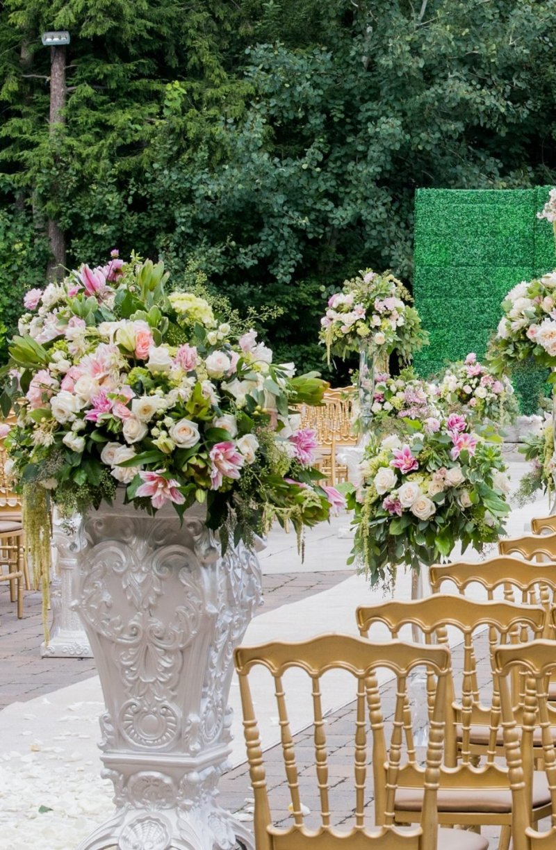 White urn of pink and white roses lining a ceremony aisle with gold chairs by GPS Decors