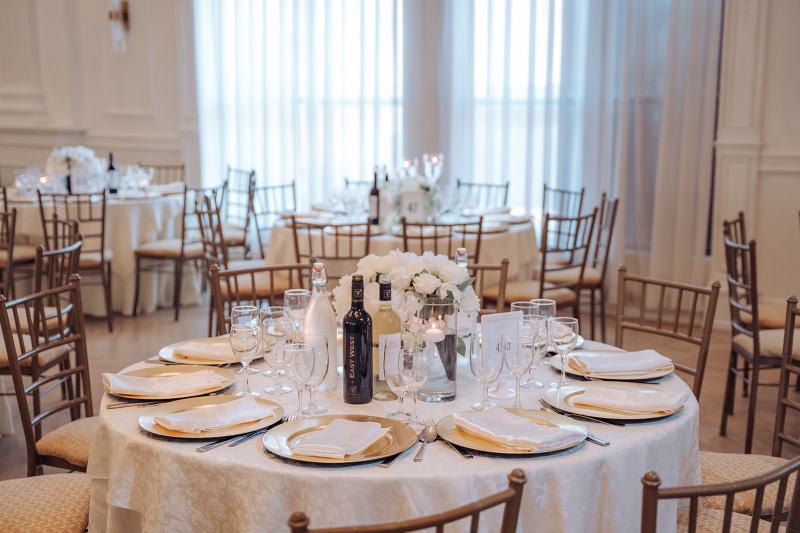 Bright reception ballroom with gold chargers and white centrepieces by GPS Decors