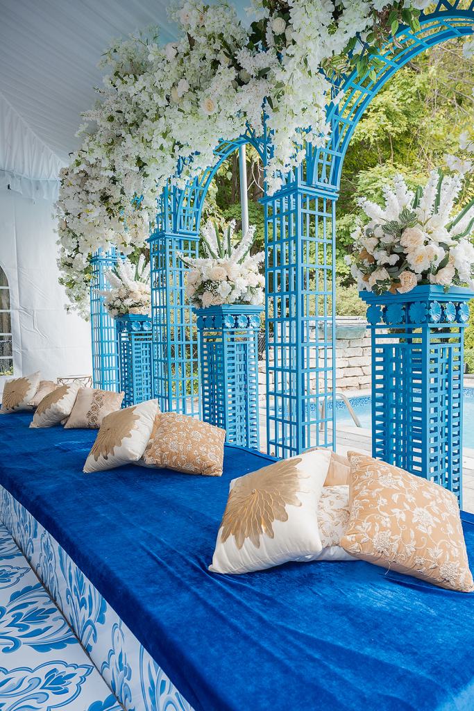 Sangeet lounge with blue lattice towers, white florals and gold cushions by GPS Decors