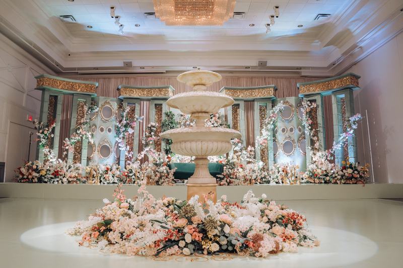 Tiered stone fountain surrounded by lush florals in a ballroom by GPS Decors