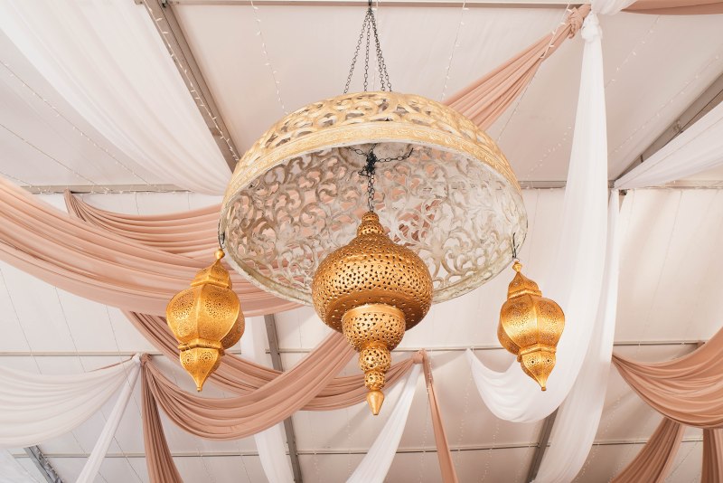 Gold Moroccan lantern hanging from a draped tent ceiling by GPS Decors