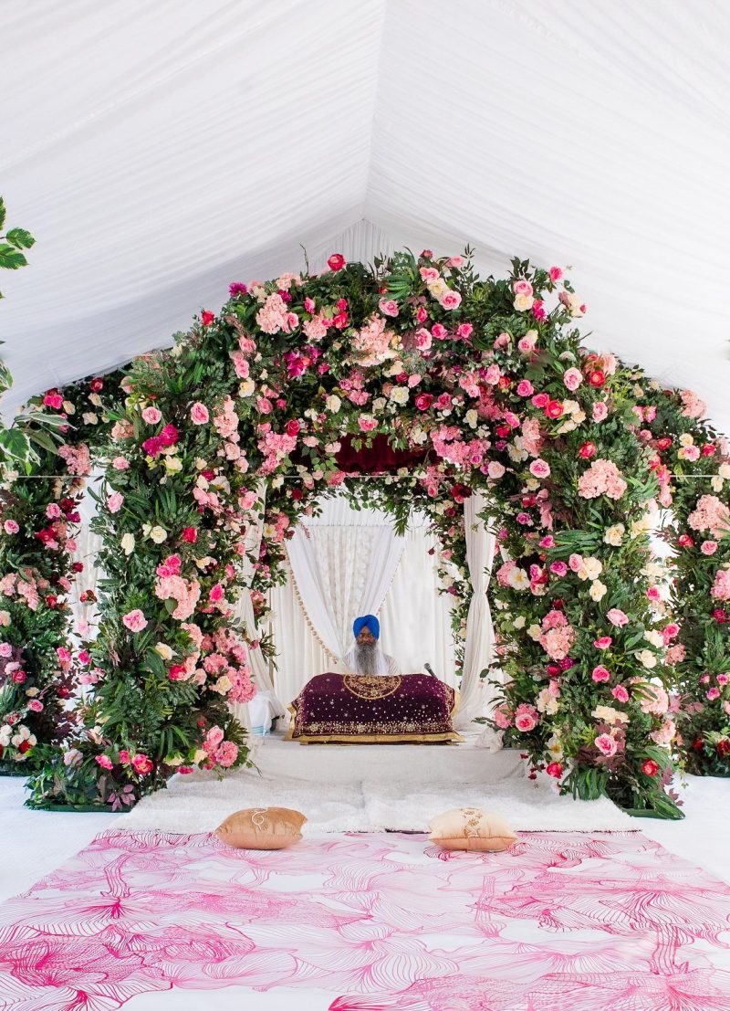 Pink rose and greenery floral arch palki inside a white tent with a pink botanical-print floor.