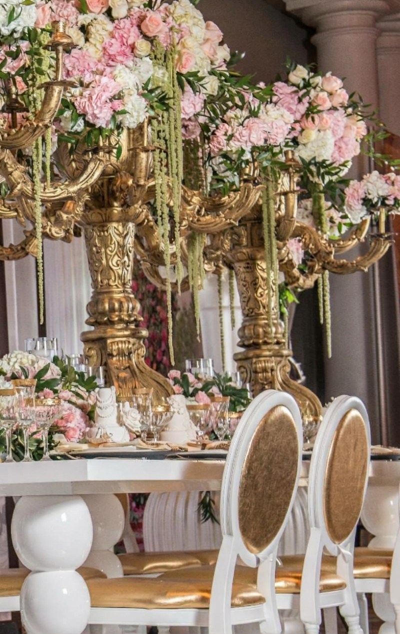 Gold candelabra centrepieces with pink roses and hanging amaranthus above white tables at Liberty Grand by GPS Decors