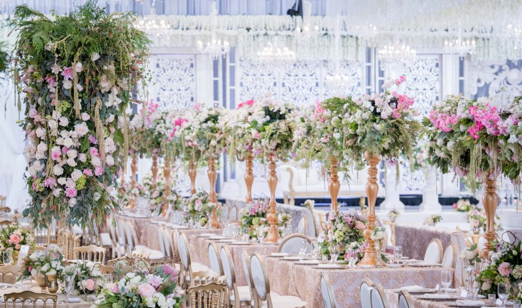 Reception at Universal Eventspace with a floral column, tall pink and white centrepieces on gold stands and blush long tables by GPS Decors