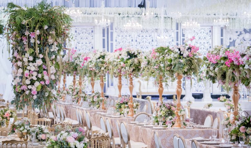 Reception at Universal Eventspace with a floral column, tall pink and white centrepieces on gold stands and blush long tables by GPS Decors