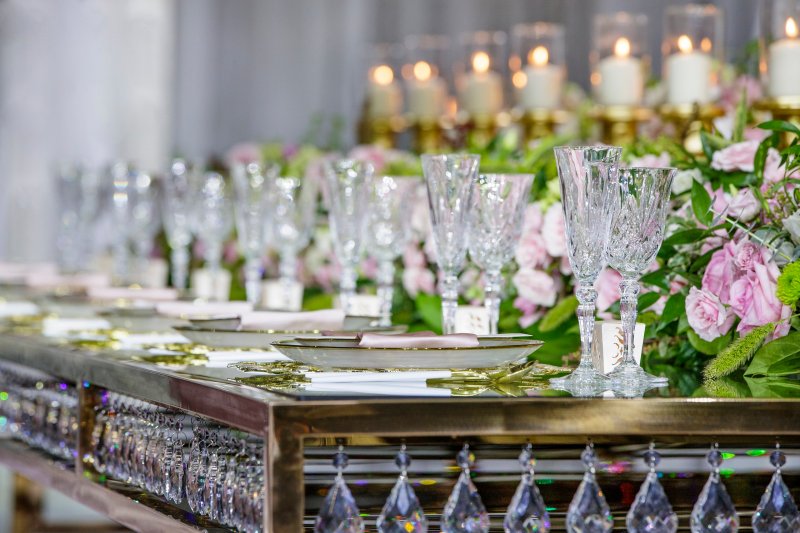 Mirrored gold table edged with crystal drops, set with a lavender rose garland, crystal glassware and candles.