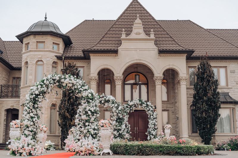 Home entrance framed by white floral arches for a wedding morning by GPS Decors