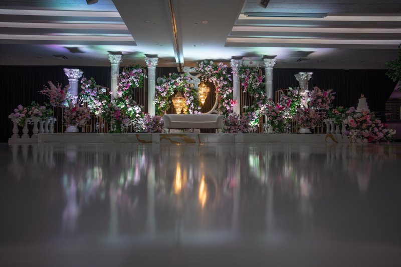 Wider view of a white column stage with pink and lavender florals and a white sofa.