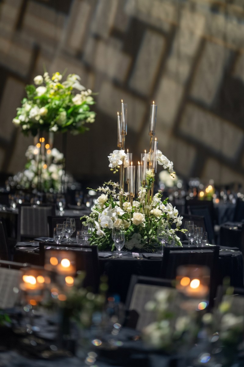Tall white floral centrepiece with candles on black reception tables at Universal Eventspace by GPS Decors