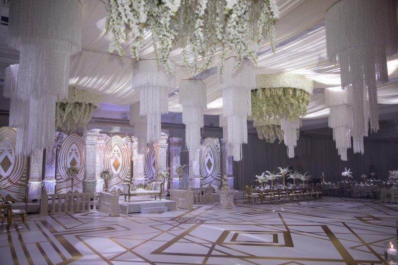 Wedding reception with a white floral ceiling installation and pillars by GPS Decors